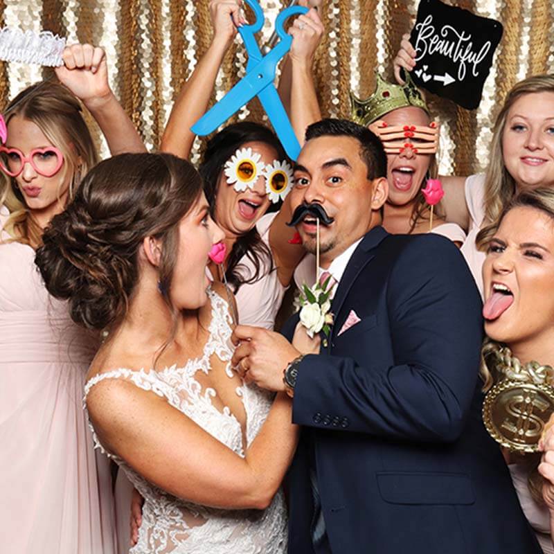 A group of wedding party goers surround a bride who is having lots of fun!